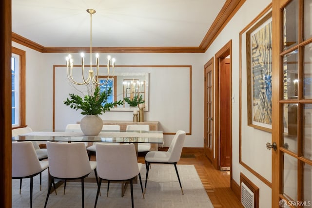 dining area with visible vents, wood finished floors, an inviting chandelier, and ornamental molding