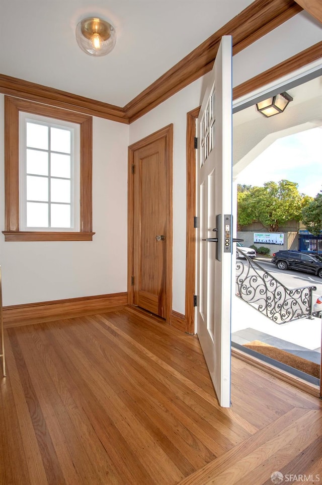 entryway featuring baseboards, light wood-style floors, and ornamental molding