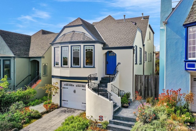 view of front of property featuring stucco siding, an attached garage, roof with shingles, and driveway