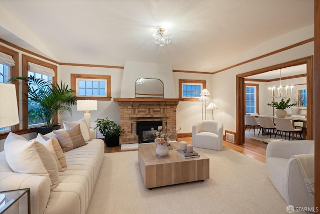 living room with visible vents, a fireplace with raised hearth, baseboards, light wood-type flooring, and a notable chandelier