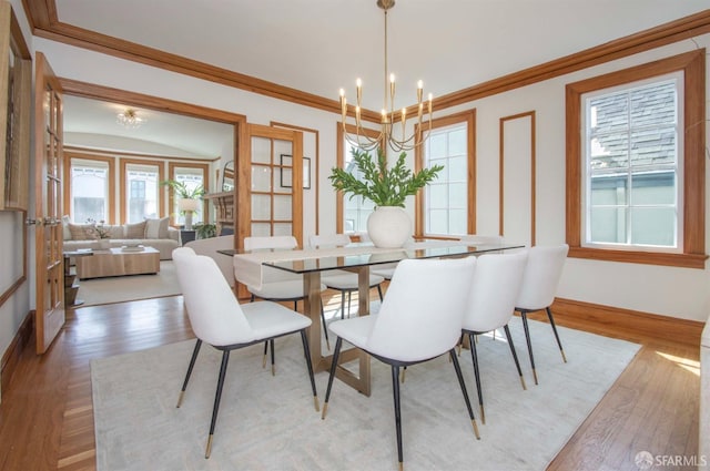 dining space featuring a chandelier, baseboards, crown molding, and light wood-style floors