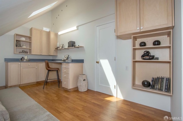 kitchen with open shelves, vaulted ceiling with skylight, and light brown cabinets