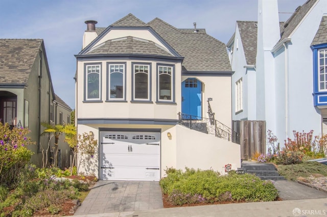 view of front facade featuring a shingled roof, driveway, and stucco siding