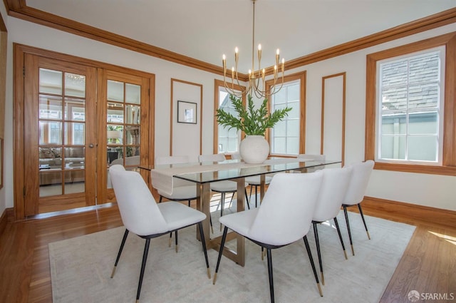 dining space with crown molding, baseboards, light wood-type flooring, french doors, and an inviting chandelier