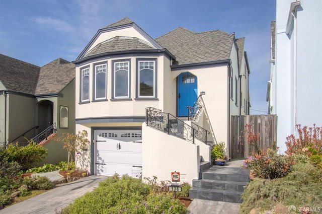 view of front of home featuring a shingled roof, concrete driveway, an attached garage, and stucco siding