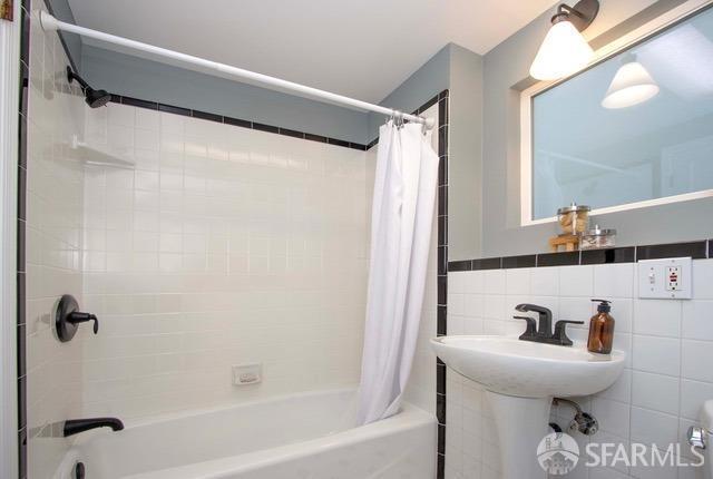 full bathroom featuring shower / bath combination with curtain and tile walls