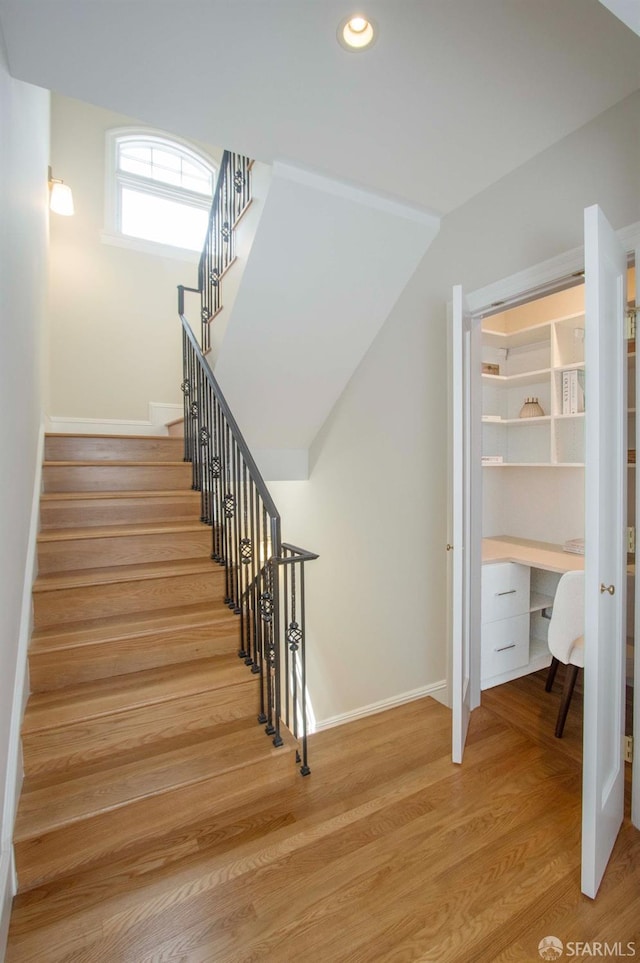 stairs featuring recessed lighting, baseboards, wood finished floors, and built in desk