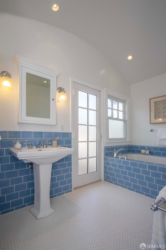 bathroom with a wainscoted wall, recessed lighting, vaulted ceiling, tile walls, and tile patterned floors