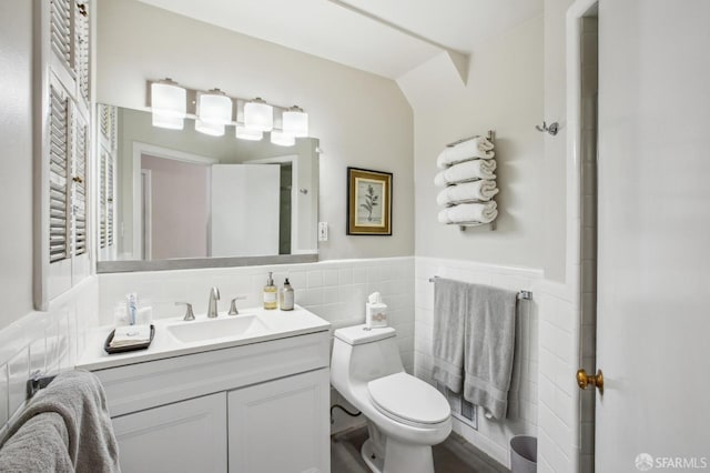 bathroom with vanity, toilet, and tile walls