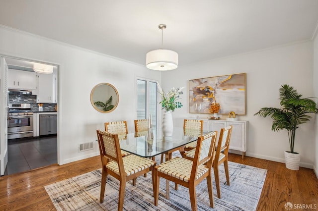 dining space featuring ornamental molding and hardwood / wood-style floors