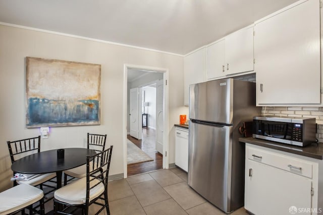 kitchen with stainless steel appliances, light tile patterned floors, white cabinets, and decorative backsplash