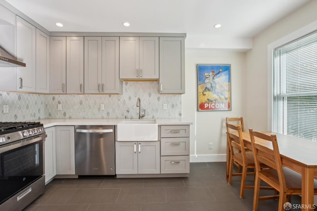 kitchen with appliances with stainless steel finishes, sink, gray cabinetry, backsplash, and dark tile patterned flooring