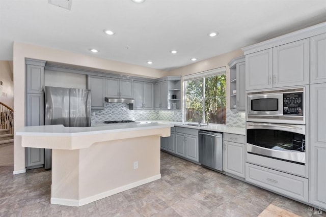 kitchen with gray cabinets, a kitchen island, sink, a kitchen bar, and stainless steel appliances