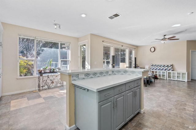 kitchen featuring a kitchen island, gray cabinetry, and ceiling fan