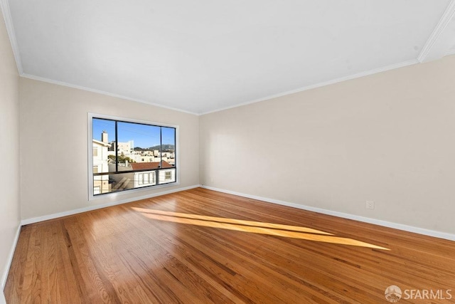 empty room with ornamental molding, baseboards, and wood finished floors