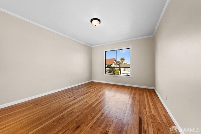 spare room with baseboards, wood finished floors, and ornamental molding