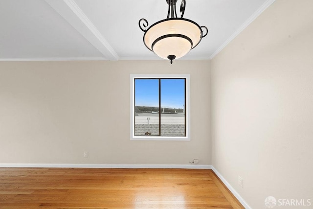 spare room with crown molding, wood finished floors, and baseboards