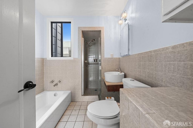 bathroom featuring a garden tub, toilet, tile walls, tile patterned floors, and a stall shower