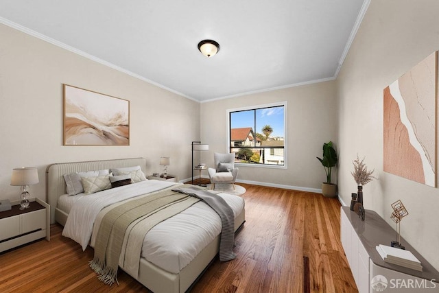 bedroom featuring ornamental molding, baseboards, and wood finished floors