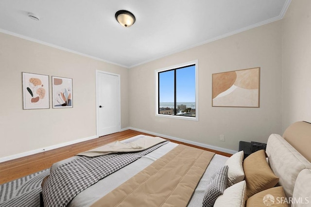 bedroom featuring crown molding, baseboards, and wood finished floors