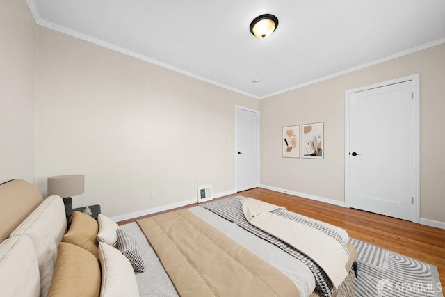 bedroom with baseboards, visible vents, wood finished floors, and ornamental molding