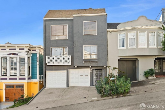 multi unit property with an attached garage, concrete driveway, and stucco siding