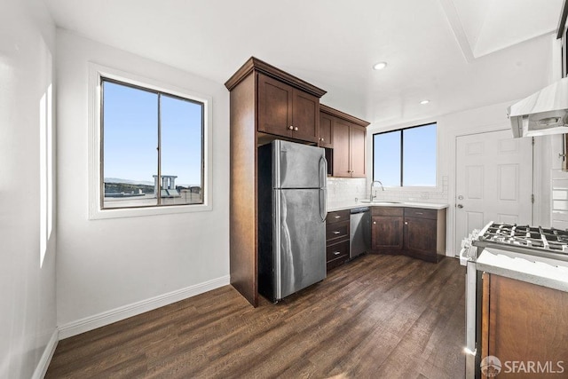 kitchen featuring decorative backsplash, dark wood finished floors, appliances with stainless steel finishes, dark brown cabinets, and a sink