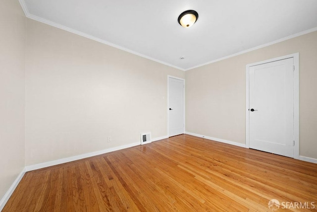 empty room with baseboards, visible vents, crown molding, and light wood finished floors