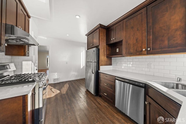 kitchen with under cabinet range hood, stainless steel appliances, dark wood-type flooring, visible vents, and light countertops