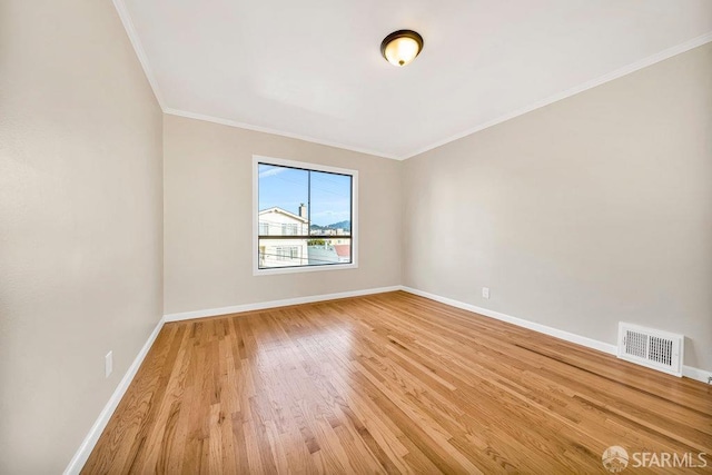 spare room featuring baseboards, visible vents, light wood-style flooring, and ornamental molding