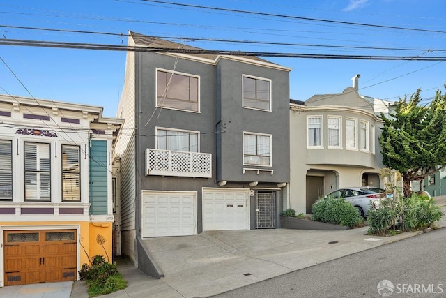 multi unit property featuring a garage, driveway, and stucco siding