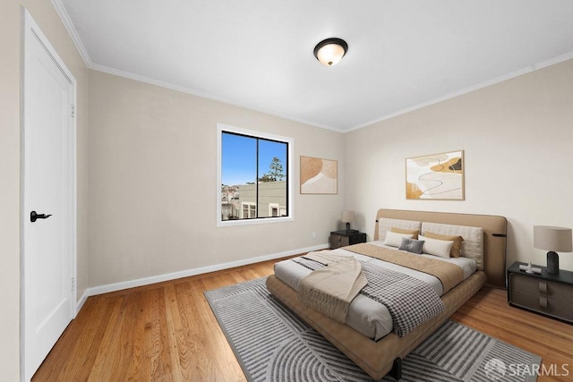 bedroom with crown molding, baseboards, and wood finished floors