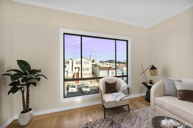 sitting room with crown molding, wood finished floors, and baseboards