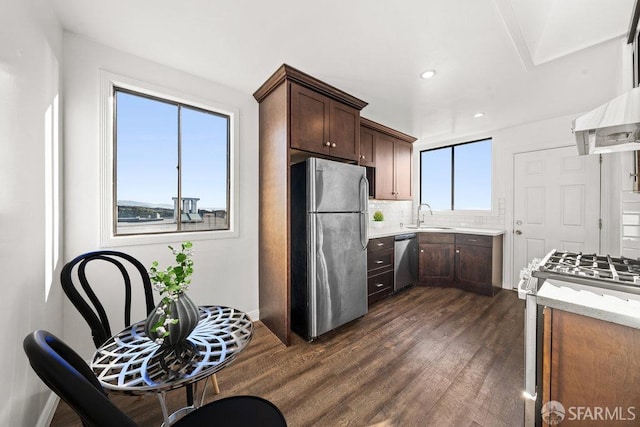 kitchen with dark wood-style flooring, decorative backsplash, appliances with stainless steel finishes, a sink, and dark brown cabinets