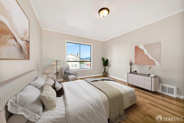 bedroom featuring ornamental molding, visible vents, baseboards, and wood finished floors