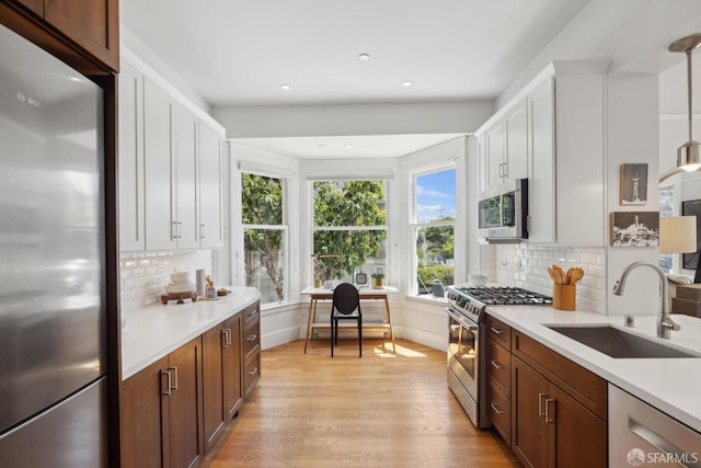 1500 Mcallister St Unit A, San Francisco, CA 94115 - kitchen with appliances with stainless steel finishes, a sink, light wood-type flooring, light countertops, and decorative backsplash