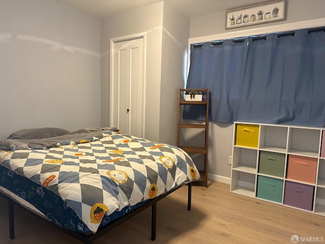 bedroom with light hardwood / wood-style floors and a closet