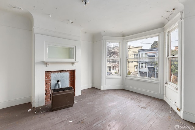 unfurnished living room with a wealth of natural light, baseboards, hardwood / wood-style floors, and a fireplace