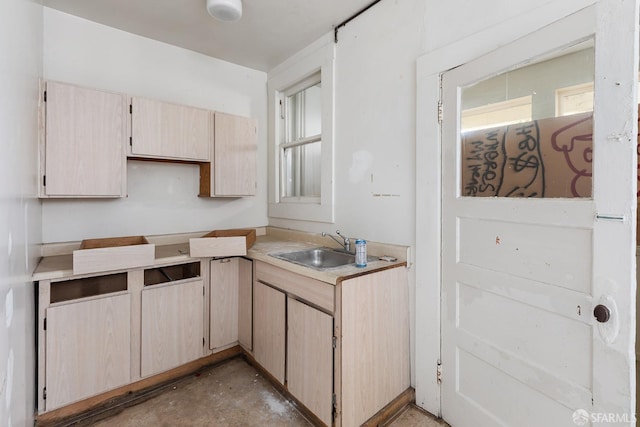 kitchen with light brown cabinets, light countertops, unfinished concrete flooring, and a sink