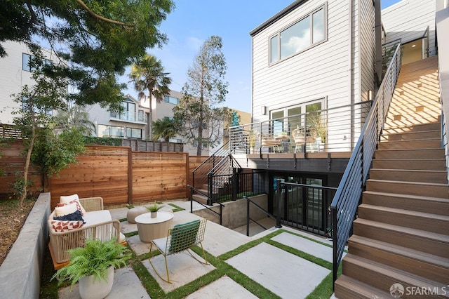 view of patio / terrace featuring a fenced backyard, stairs, and an outdoor living space