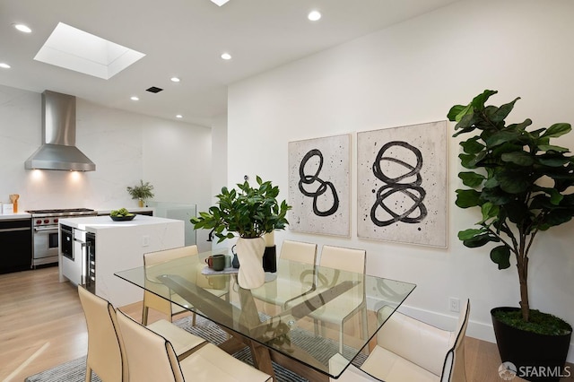 dining room with light wood-type flooring, a skylight, visible vents, and recessed lighting