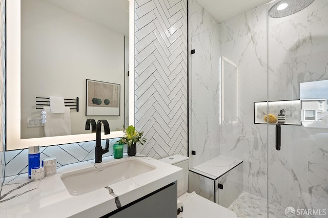 bathroom featuring toilet, a marble finish shower, and vanity