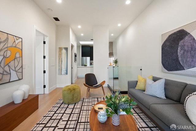 living area featuring light wood-type flooring, baseboards, visible vents, and recessed lighting