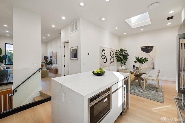 kitchen with a skylight, visible vents, a center island, light wood-type flooring, and recessed lighting