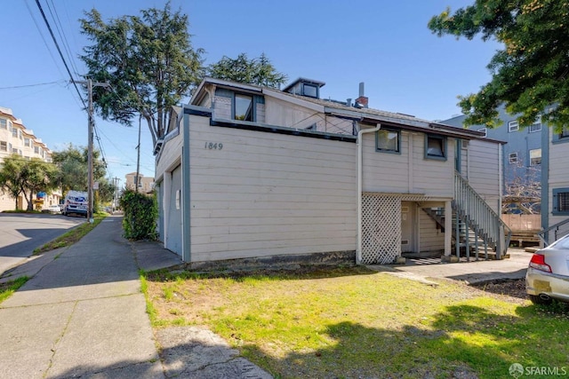 back of house with a yard and stairway