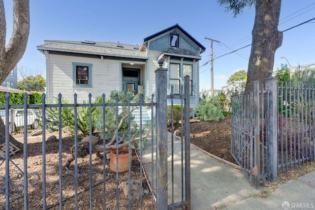 view of front of house featuring a gate, a shingled roof, and a fenced front yard