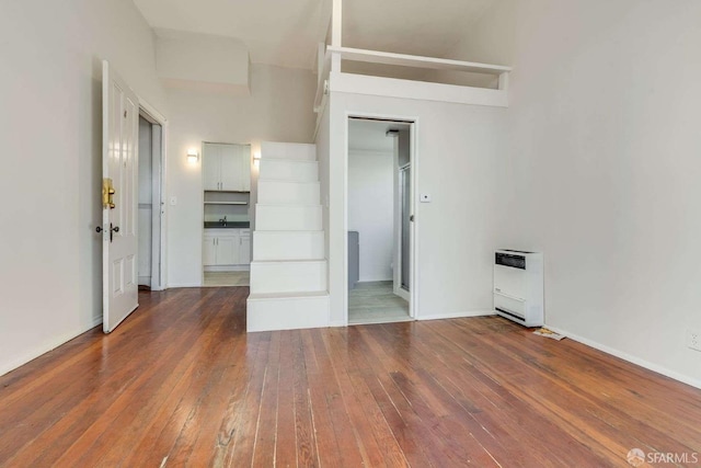 unfurnished bedroom featuring baseboards, dark wood finished floors, and heating unit