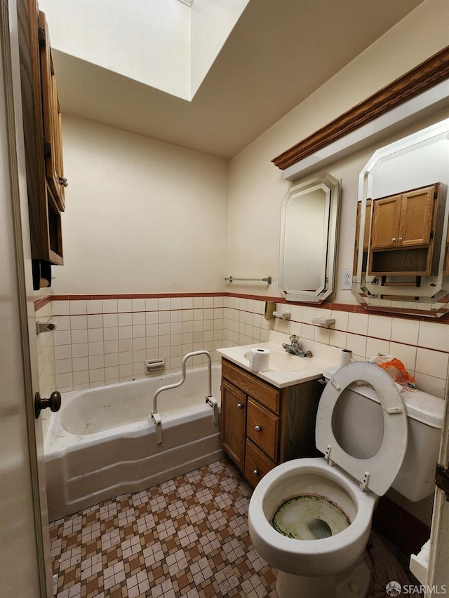 bathroom with vanity, toilet, a bathtub, and tile walls