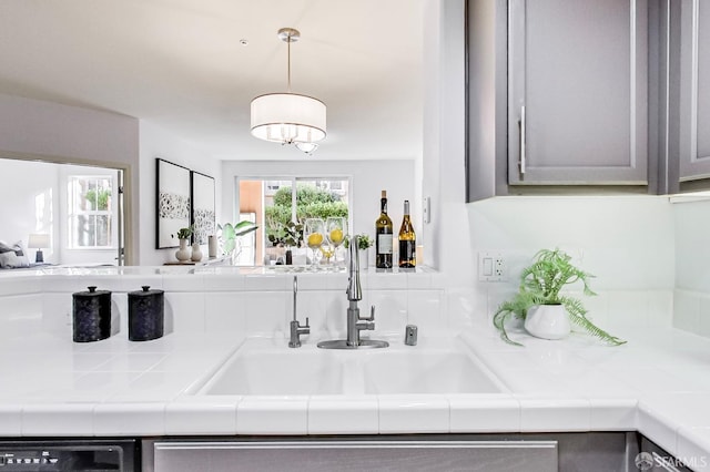 bar with sink, gray cabinetry, tile countertops, dishwasher, and pendant lighting