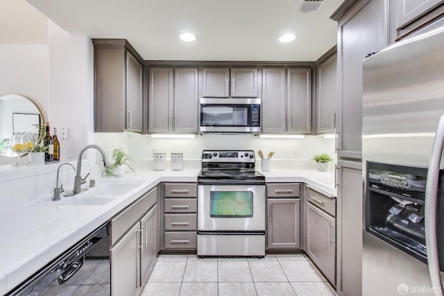 kitchen with appliances with stainless steel finishes, sink, and light tile patterned floors